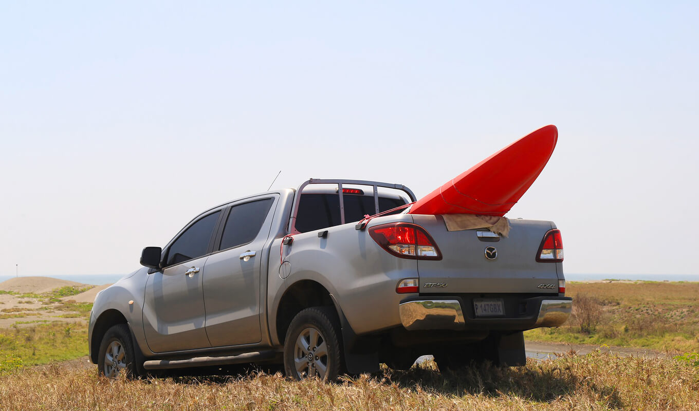 Red kayak on the back of a gray pick up truck